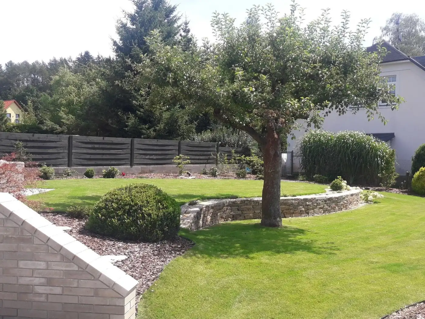 Udržovaná zahrada s trávníkem, zídkou a výsadbou